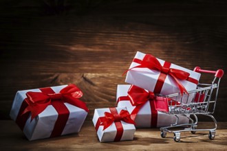 Set of white gift boxes with shopping trolley on vintage wood