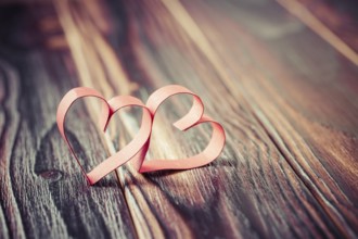 Two paper hearts on wooden background in vintage look - soft focus. Symbol of love. Space for text
