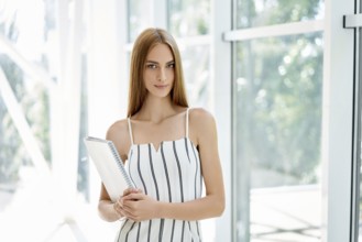 Confident business woman holding documents and looking at camera in modern creative office