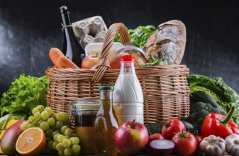 Wicker basket with assorted grocery products including fresh vegetables and fruits