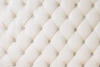 Beige soft tapestry pattern background with symmetrical buttons on the corners of diamonds. Soft