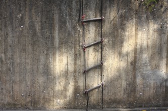 Rope ladder on a concrete wall with sunlight reflections