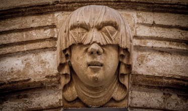 Gothic detail. Young woman portrait at the entrance of a 200 years old building in Ciutadella town,
