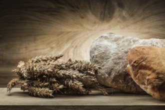 Loafs of bread and ears on vintage wood