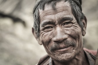 Dolpo, Nepal, circa May 2012: Old wrinkled man with grey hair and moustache smiles nicely to