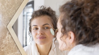 Woman looking mirror doing face massage 4