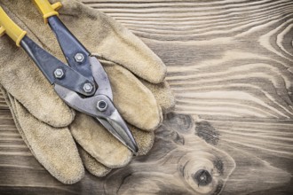 Pair of safety gloves steel cutter on vintage wooden board construction concept