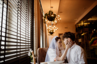 An intimate moment between a bride and groom inside a warmly lit room with chandeliers