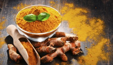 Composition with bowl of turmeric powder on wooden table