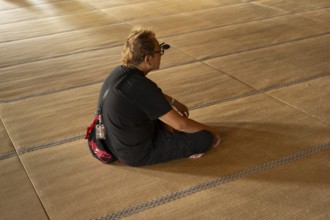 Tourist with glasses meditating on the tatami, Higashi Hongan-ji, Kyoto, Japan, Asia