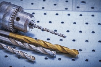 Metal drill with boring bits on perforated metallic sheet construction concept