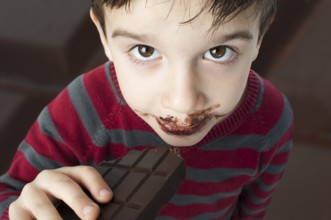 Smiling kid eating chocolate. Smeared stained with chocolate lips