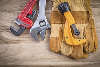 Safety gloves adjustable key monkey wrench pipe cutter on wood board plumbing concept