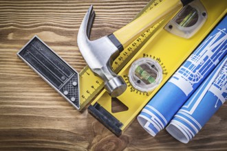 Blue engineering drawings construction level square ruler claw hammer on wooden board