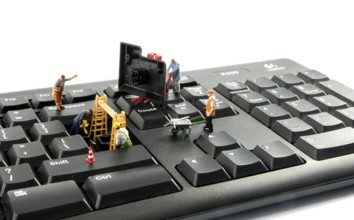 Little world figures repairing the key board of the computer or try to hack or intergate in the