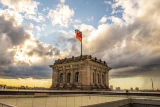 The Berlin Reichstag with evening sky with the flag of Germany and clouds in the background. The