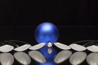 Blue Christmas decoration and six spoons on a black glass desk