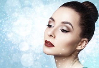 Portrait of young and beautiful woman with evening make-up over winter Christmas background