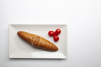 Diet breakfast. French baguette and red cherry tomatoes on the white table