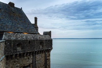 View of the ramparts of Mont Saint Michel with the tide coming in at sunset. Normandy, France,