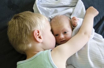 Baby with big eyes beeing cuddled by his older brother, Copenhagen, Denmark, Europe