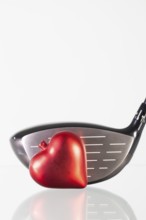 Golf club and red heart on a glass table