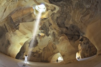 Yoga classes in the cave Beit Guvrin, Israel. Woman in white performs asana Sun salutation