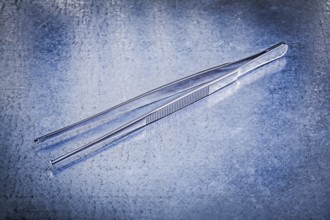 Pair of tweezers on metallic background medicine concept
