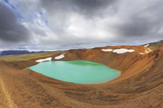 Lake water bright green color. On the shores lie snowfields from last year. Picturesque lake in the