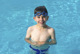 Child in swiming pool. Blue glasses