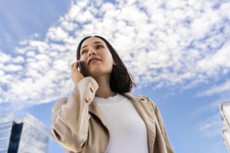 Low-angle view of a woman talking on her cell phone as she looks ahead
