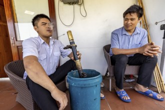 Two men on a terrace, one blowing out smoke, adding to the relaxed and casual atmosphere, Two men