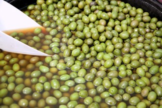Brine green olive fruits in market round pot