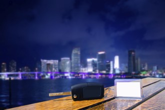 Car rental keys on wood table with blank paper in Miami night downtown