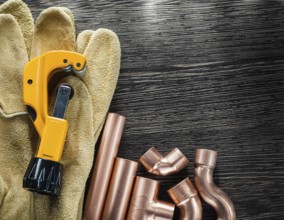Plumbing water pipe scissors leather protective gloves on wooden board