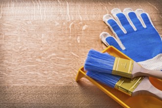 Wooden board with protective gloves paint tray and brushes construction concept