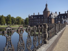 Ornate iron fence along a moat with a view of a brick castle, anholt, isselburg, münsterland,