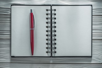 Opened notebook pen on white wooden board