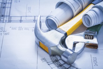 Adjustable spanner rolled up blueprints and claw hammer construction concept