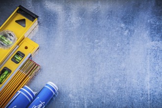Blue blueprints levels yellow wooden meter on metallic surface