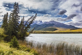 Cloudy Indian summer in the Rockies of Canada. Rocks and lakes under flying clouds. Concept of
