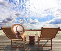 Comfortable sun loungers on a wooden platform. Delightful field of white bright spring