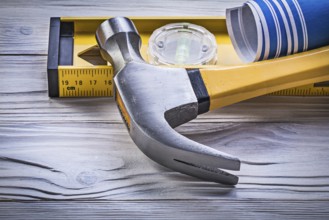 Claw hammer blue rolled engineering drawings construction level on wooden board