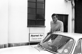 Sir Roger Moore, 1927-2017 during the filming of the tv-series The Saint, posing with a Volvo P1800