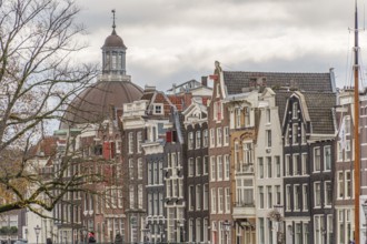 Typical Dutch house facades with gables and a church in the background, Amsterdam, Netherlands