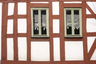The beam construction and timber frame of a half-timbered house with two narrow wooden windows