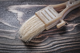 Obsolete paintbrush on wood board close up view construction concept