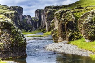 The sheer cliffs covered with green moss enclose the channel of the brook with melted water. The