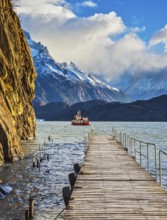 Pleasure boat for tourists swim with wooden pier. Grey Lake in the national park Torres del Paine,