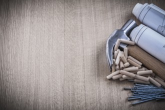 Blueprints hammer dowels nails on wooden board construction concept